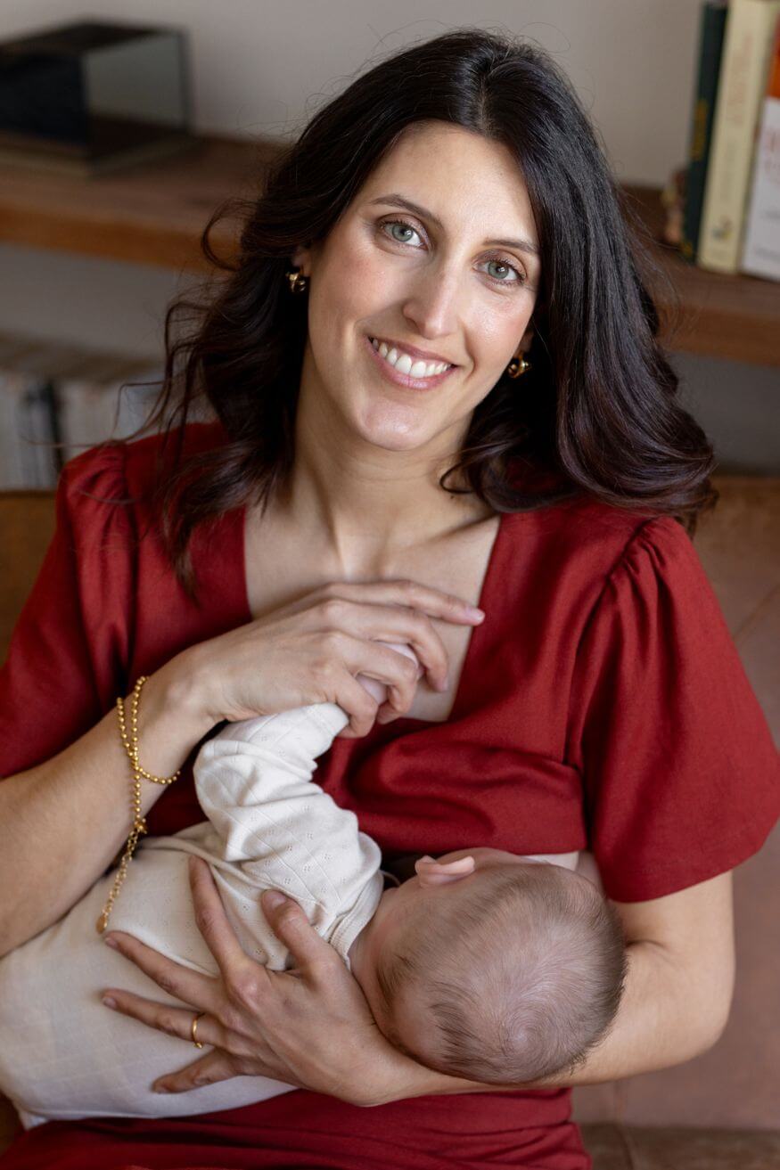 Femme qui allaite en souriant dans son haut de maternité