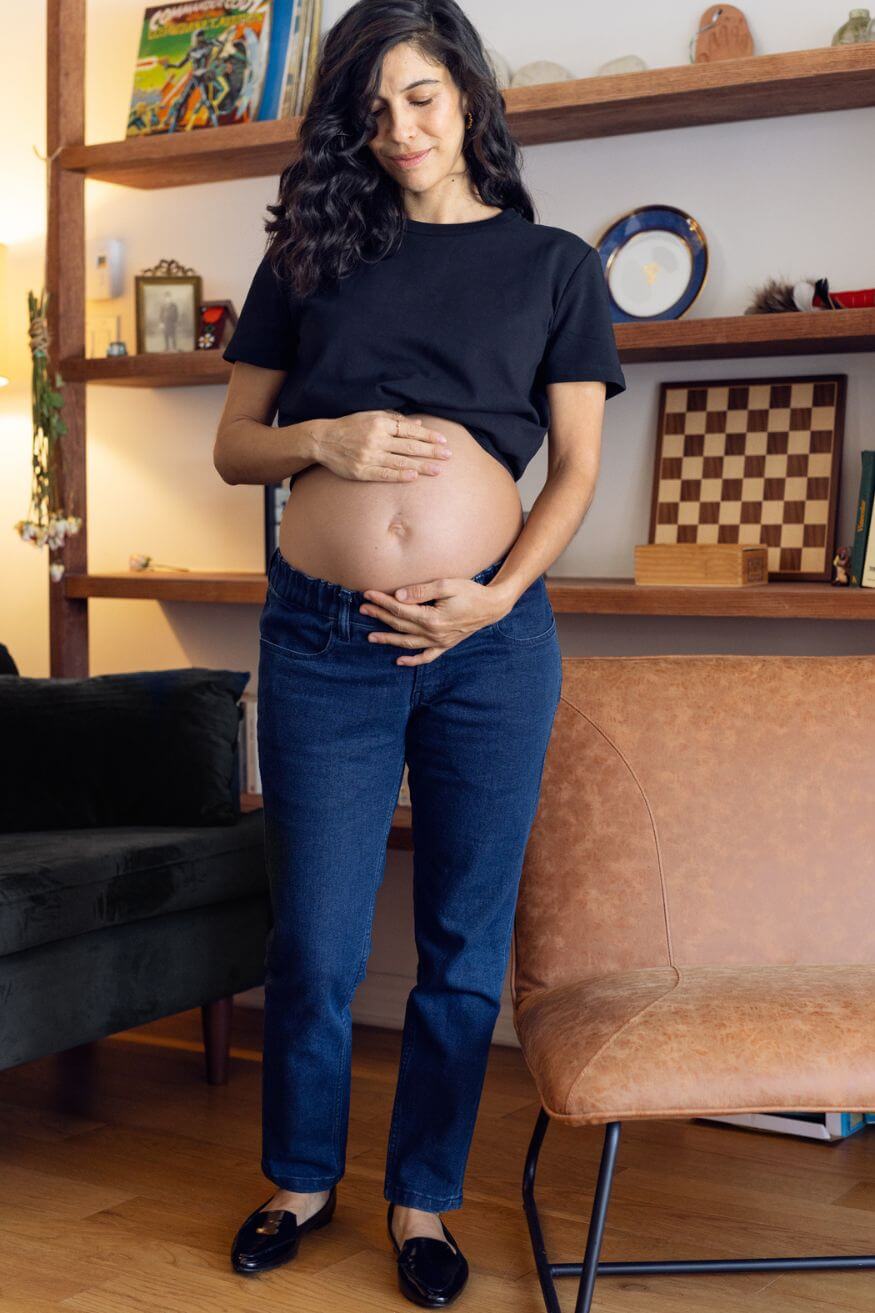 Femme enceinte mets les main sur son ventre au dessus de son jean de maternité